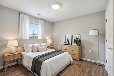 A bedroom with a large bed, nightstands, and a window with a view of a street.
