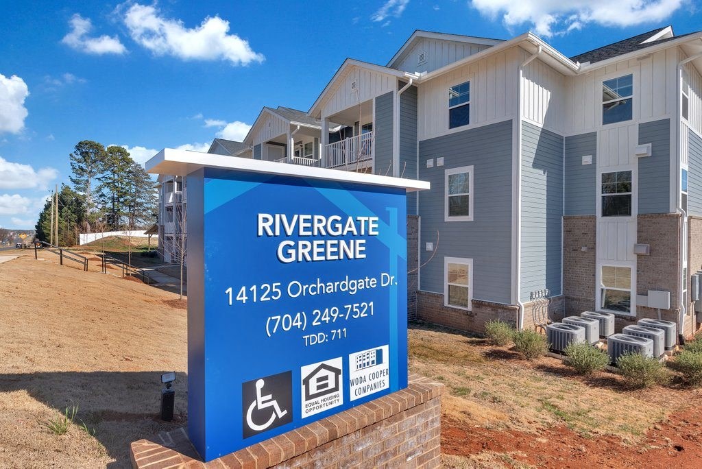 an apartment building with a sign for rivergate greene on a dirt