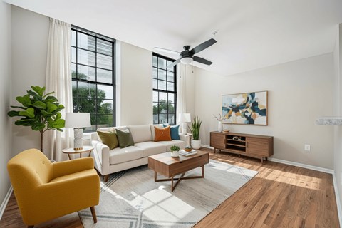 A living room with a yellow chair, a white couch, and a wooden coffee table.