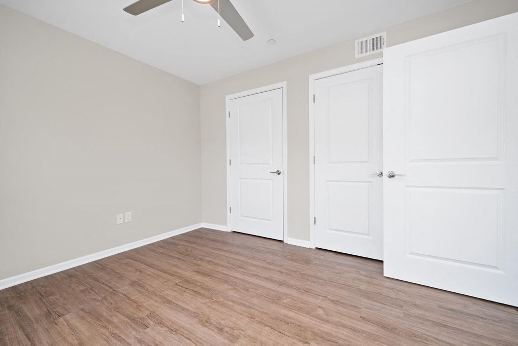 a bedroom with two doors and a ceiling fan