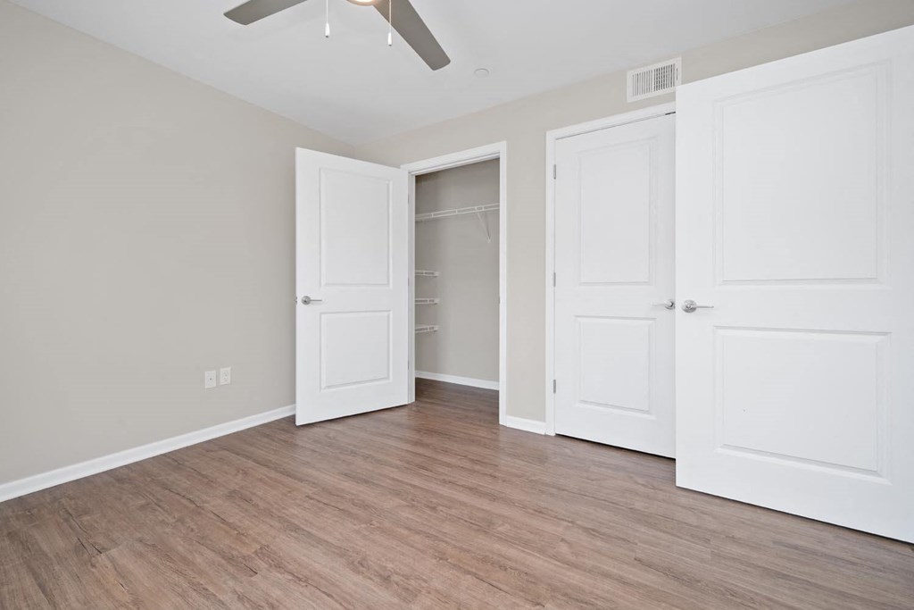 a bedroom with two doors and a ceiling fan