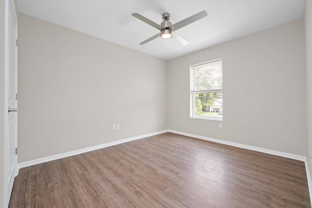 an empty room with a ceiling fan and a window