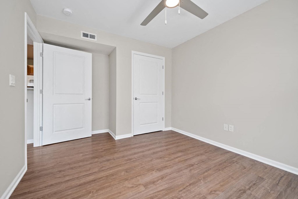 a bedroom with two doors and a ceiling fan