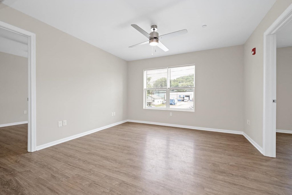 an empty room with a ceiling fan and a window