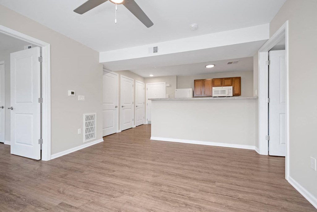 a spacious living room with a kitchen in the background
