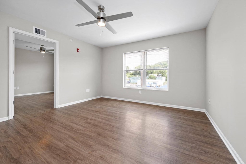 an empty room with a ceiling fan and a window