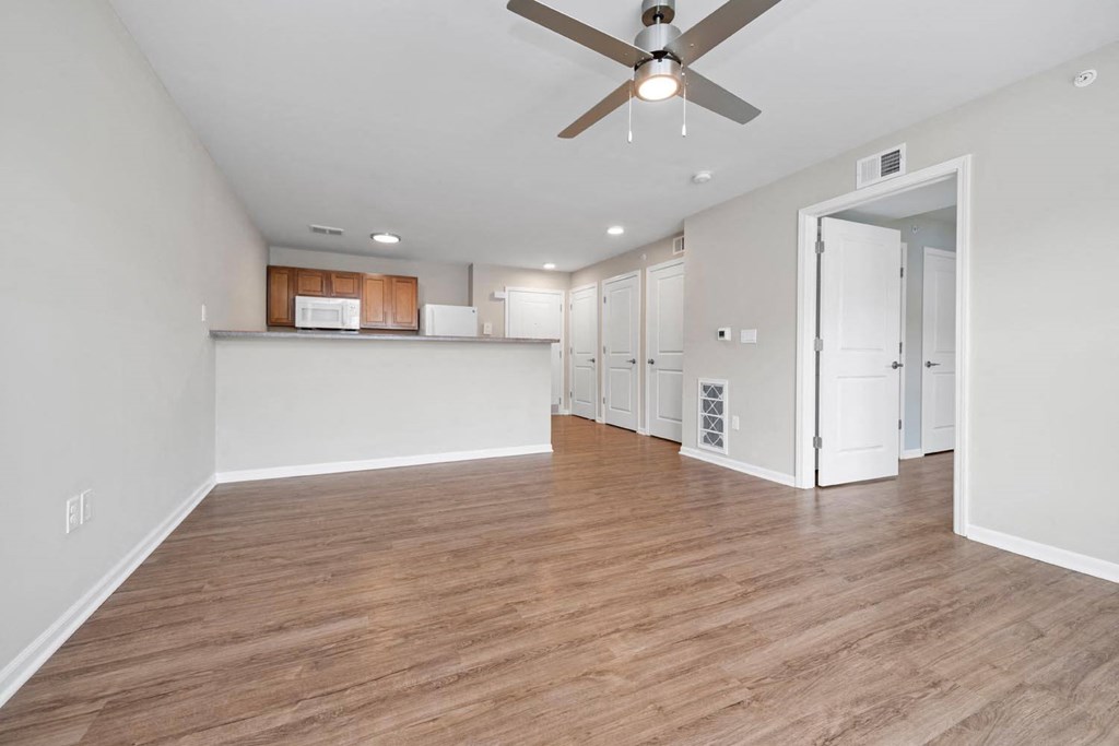 a living room and kitchen area with a ceiling fan