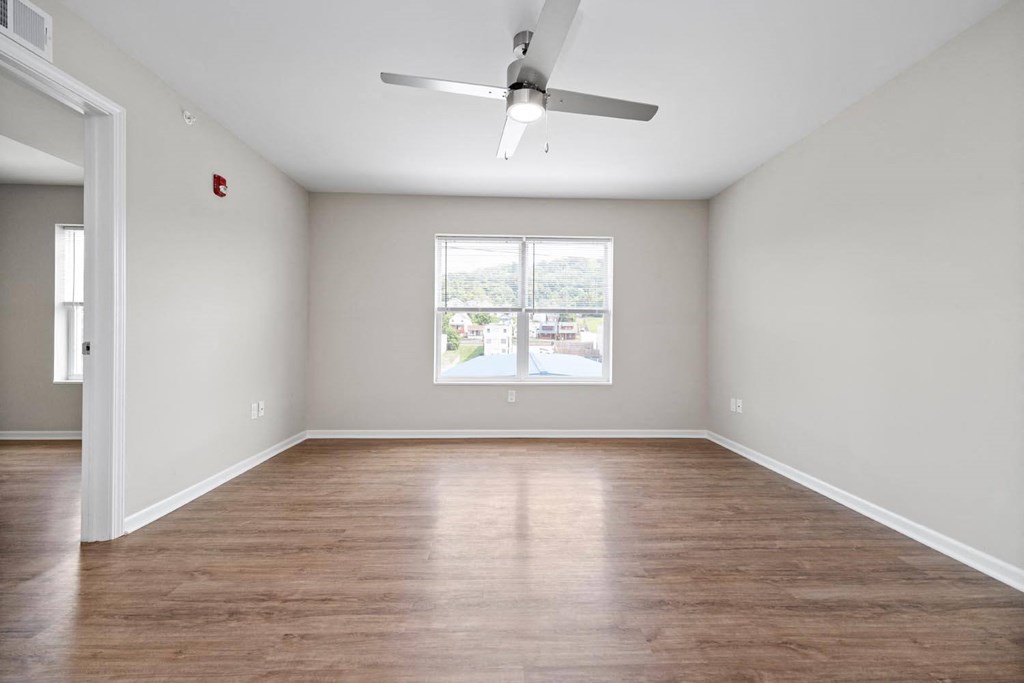 an empty room with a large window and a ceiling fan