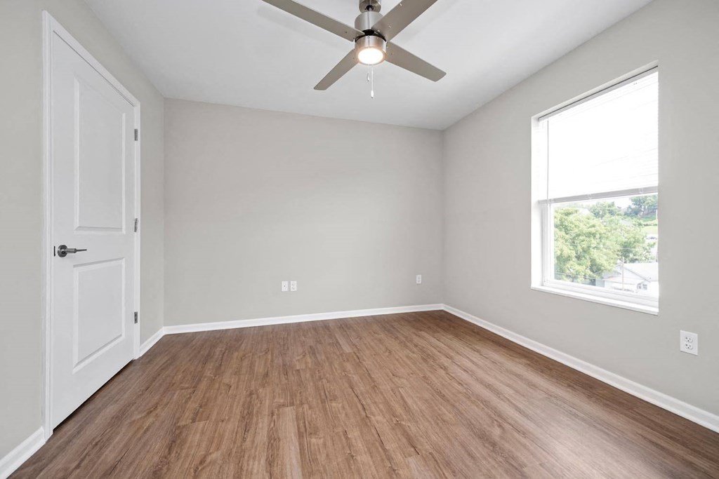 an empty room with a ceiling fan and a window
