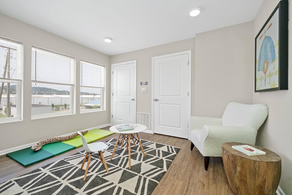 a living area with a couch coffee table and three windows
