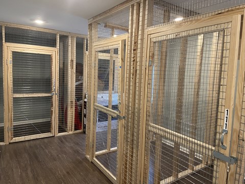 a group of cages in a room with wooden floors and doors