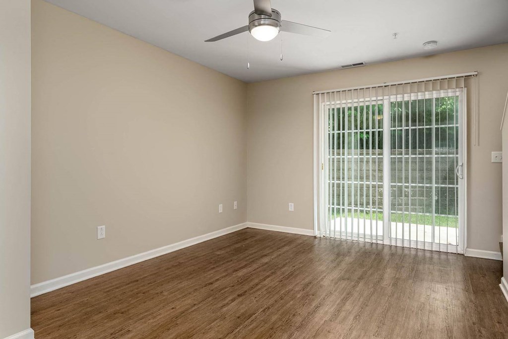 an empty room with a sliding glass door and a ceiling fan