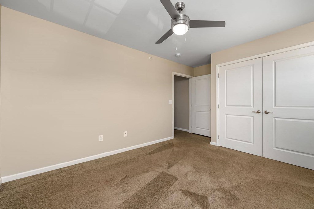 a bedroom with a ceiling fan and a door to a closet
