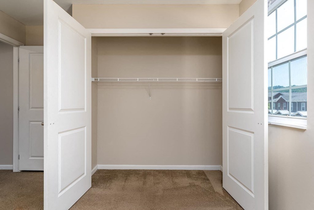a walk in closet in a bedroom with two doors and a window