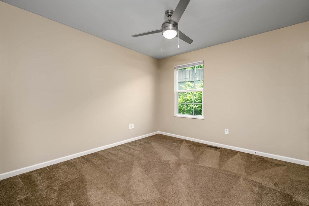 an empty room with a ceiling fan and a window