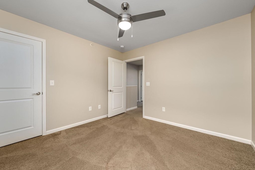 A room with a ceiling fan and carpeted floor.