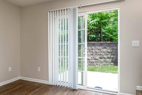 a living room with white blinds on a sliding glass door