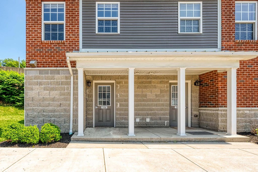 a brick building with a gray siding and a gray door