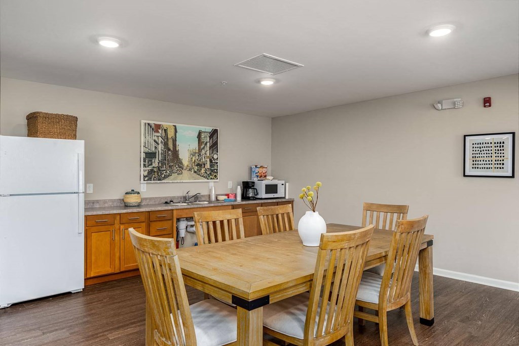 a dining area with a table and chairs and a kitchen in the background