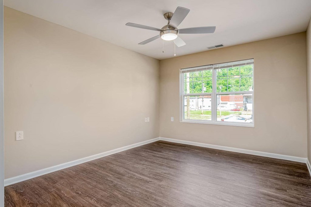 a bedroom with a large window and a ceiling fan