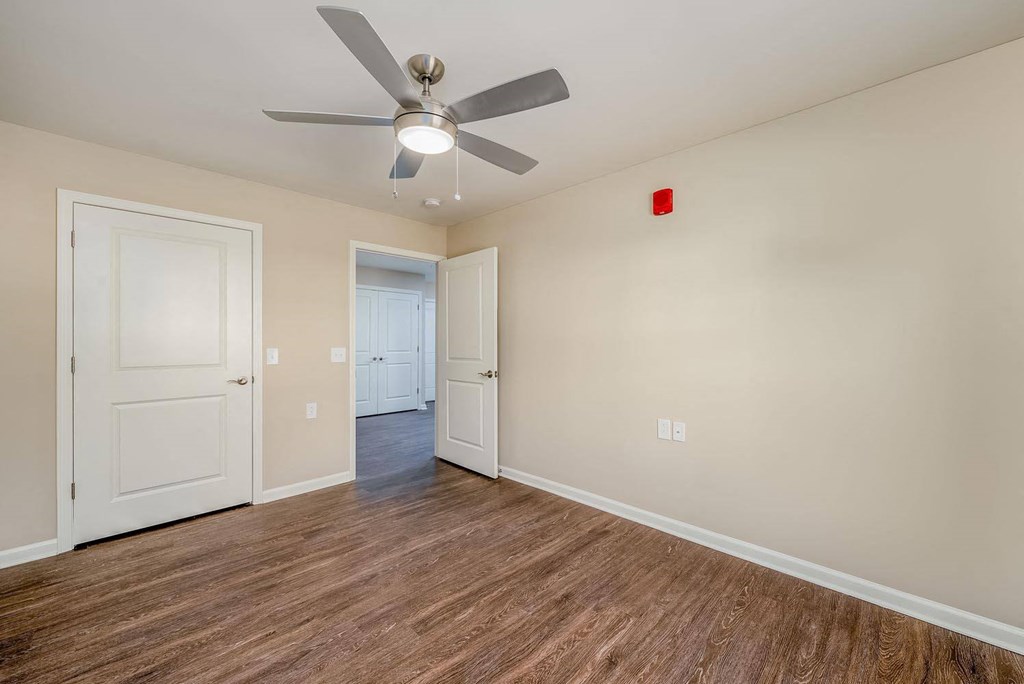 a bedroom with hardwood floors and a ceiling fan