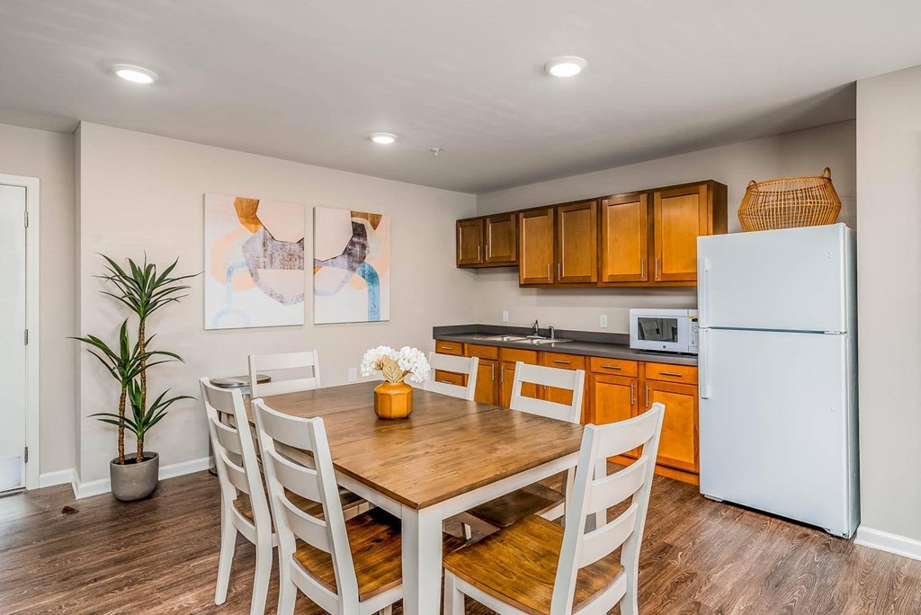 a kitchen with a wooden table and chairs and a white refrigerator