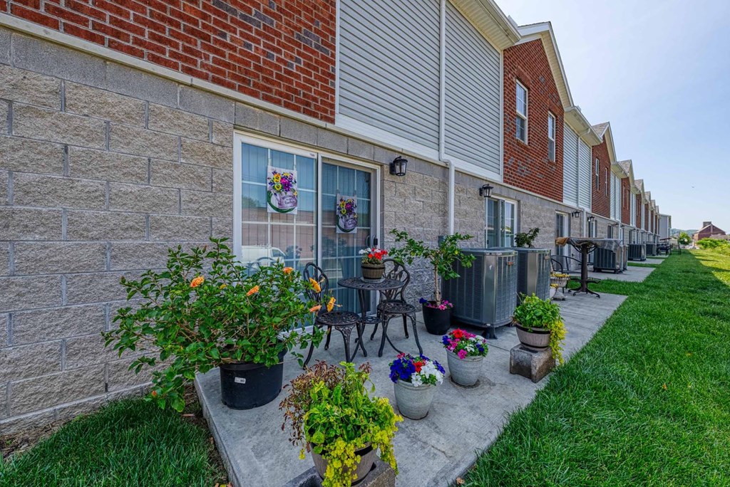a courtyard with a table and chairs and potted plants in front of a brick building