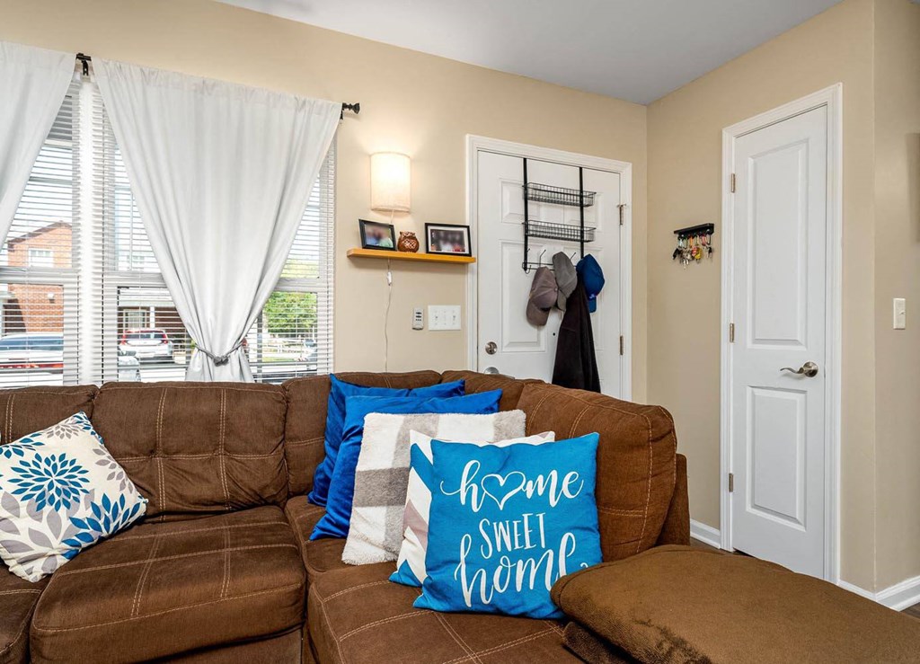 a living room with a brown couch and blue and white pillows