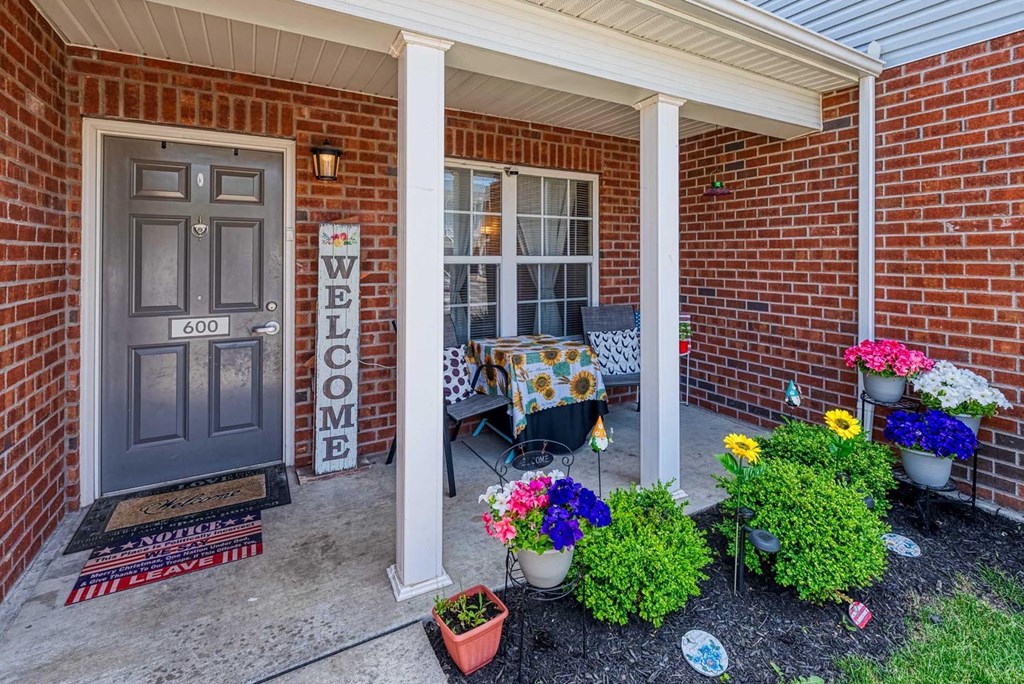 a front porch with a table and chairs and a welcome sign