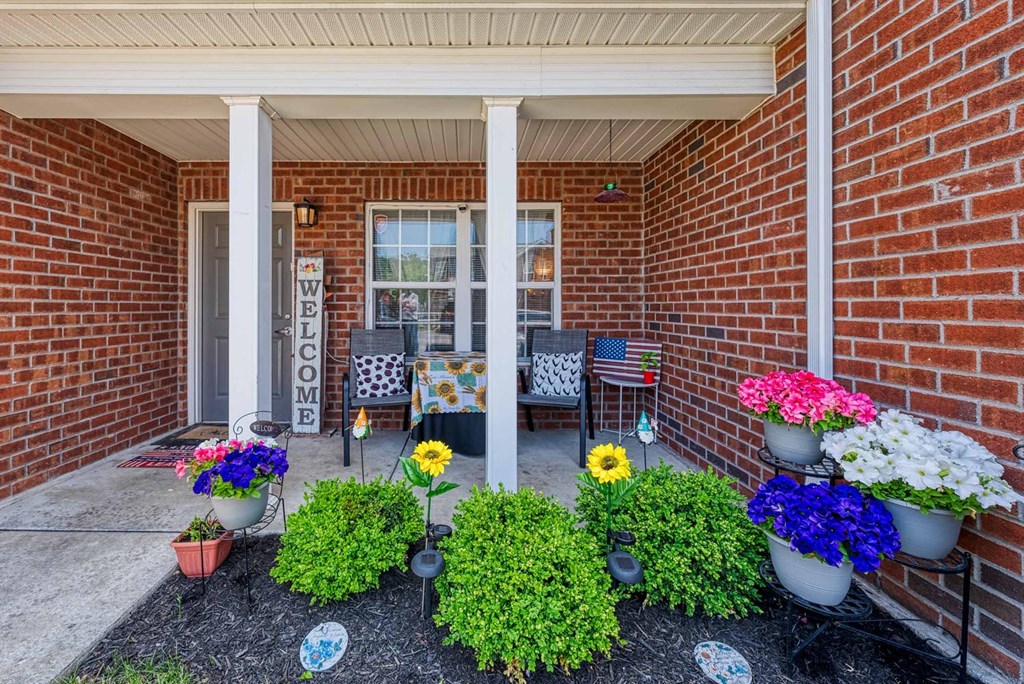 a front porch with potted flowers and chairs