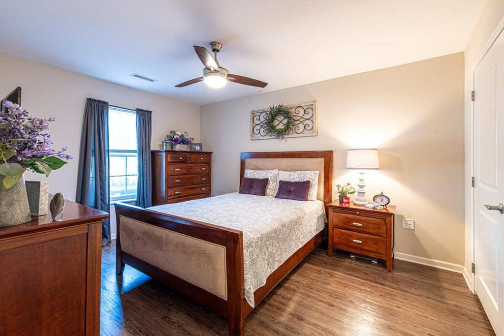 A bedroom with a bed, nightstand, and a window with curtains.