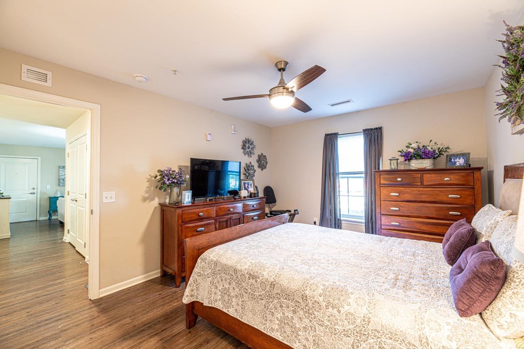 A bedroom with a bed, dresser, and ceiling fan.