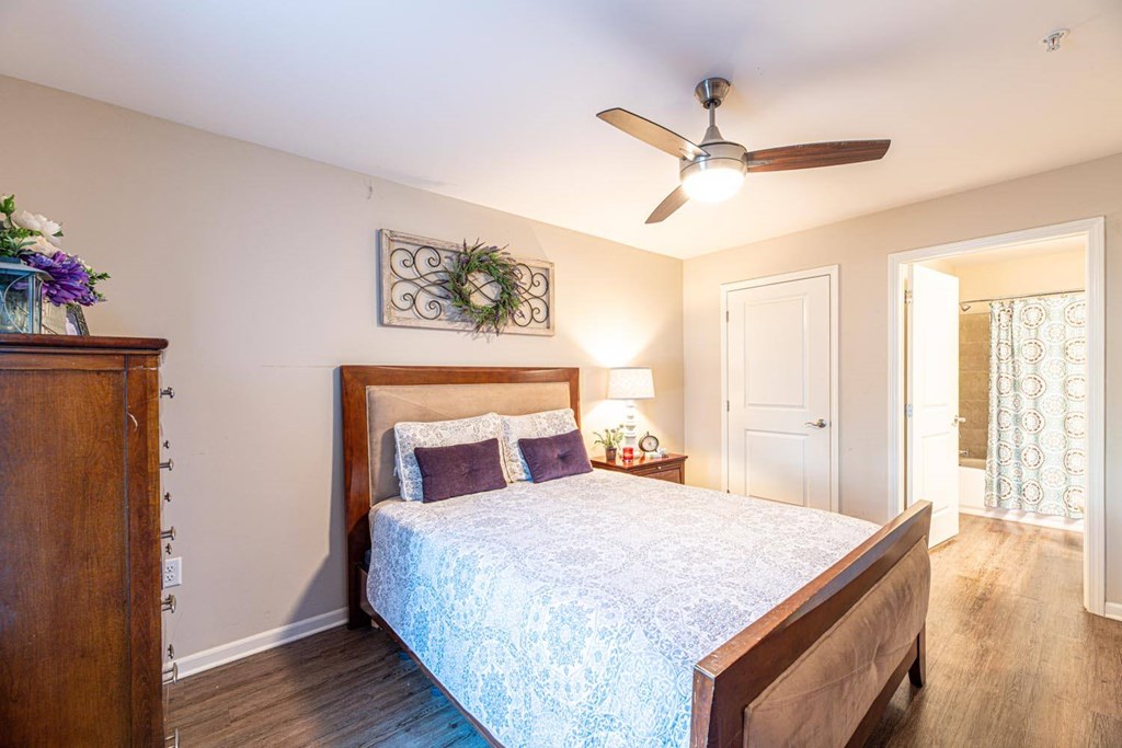A bedroom with a bed, dresser, and a ceiling fan.