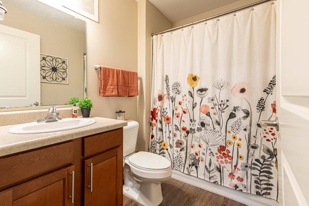 A bathroom with a floral shower curtain and a white toilet.