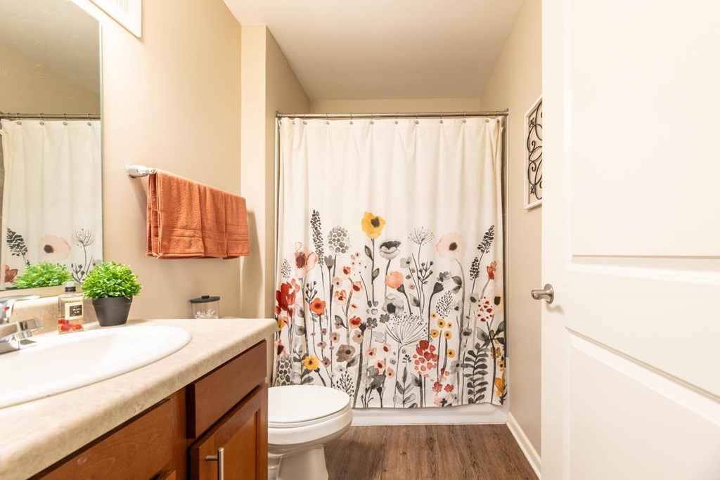 A bathroom with a floral shower curtain and a towel hanging on the towel rack.