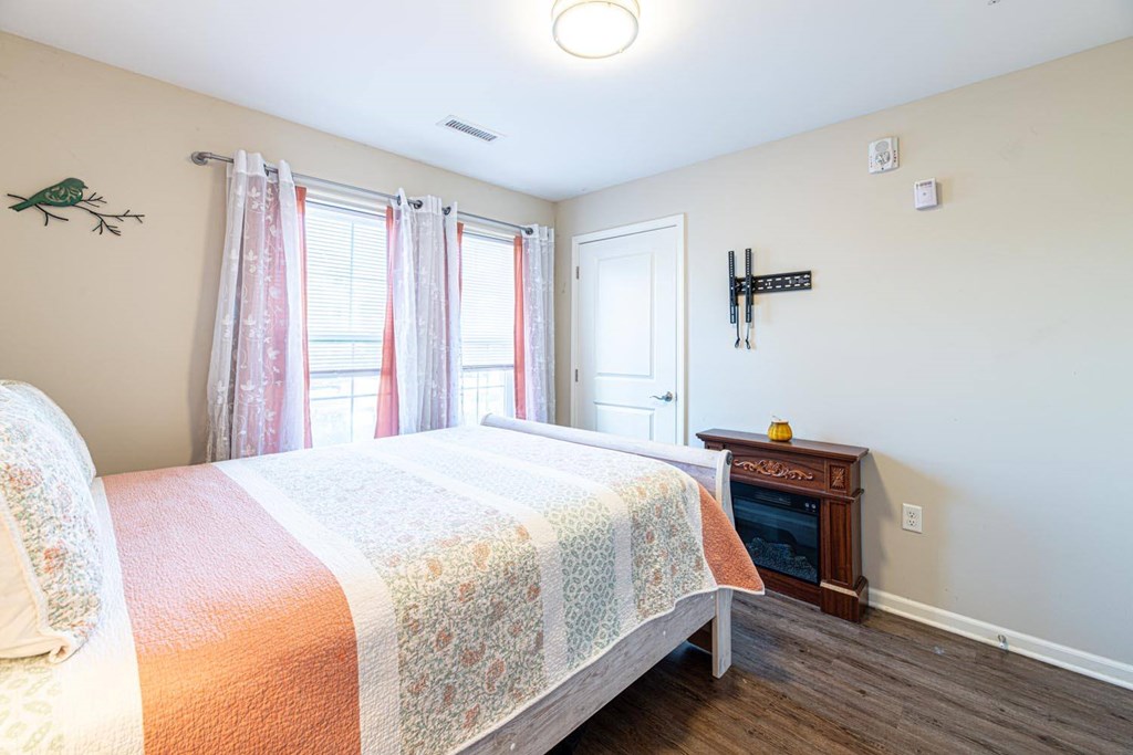 A bedroom with a bed, a window with curtains, and a wooden cabinet.