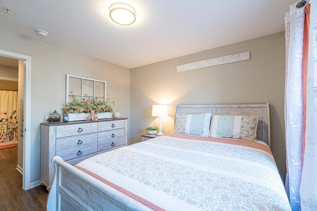 A bedroom with a bed, nightstand, and dresser.