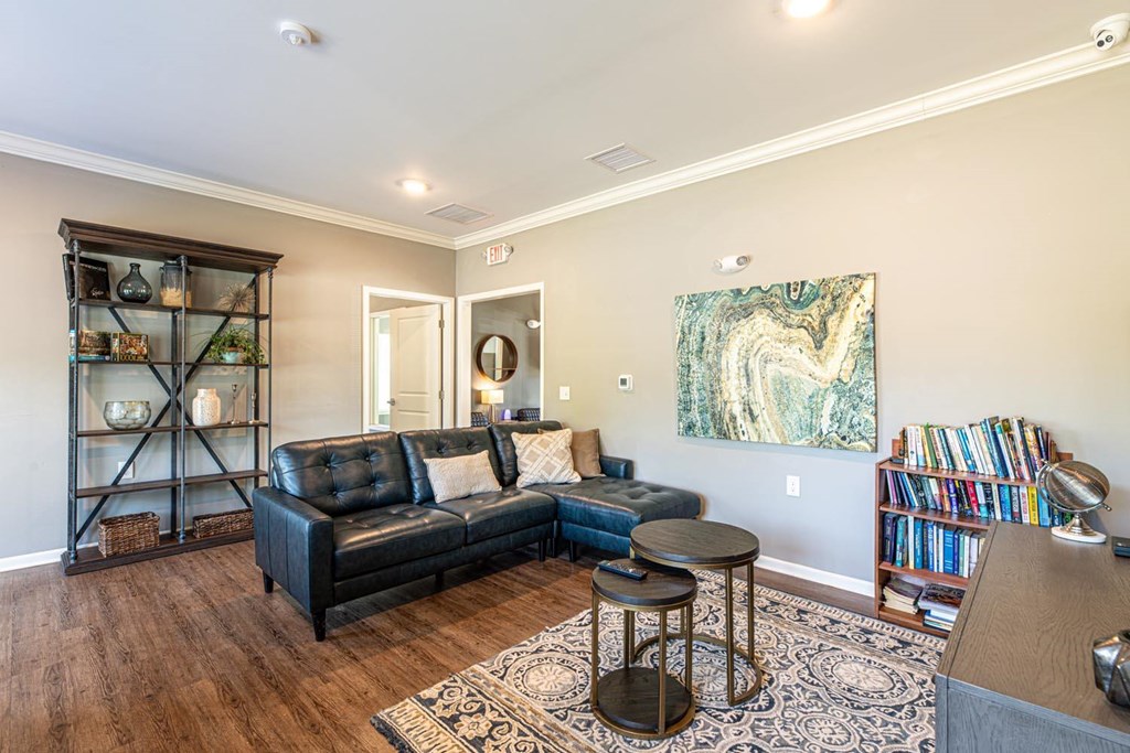 A living room with a black leather couch and a wooden floor.