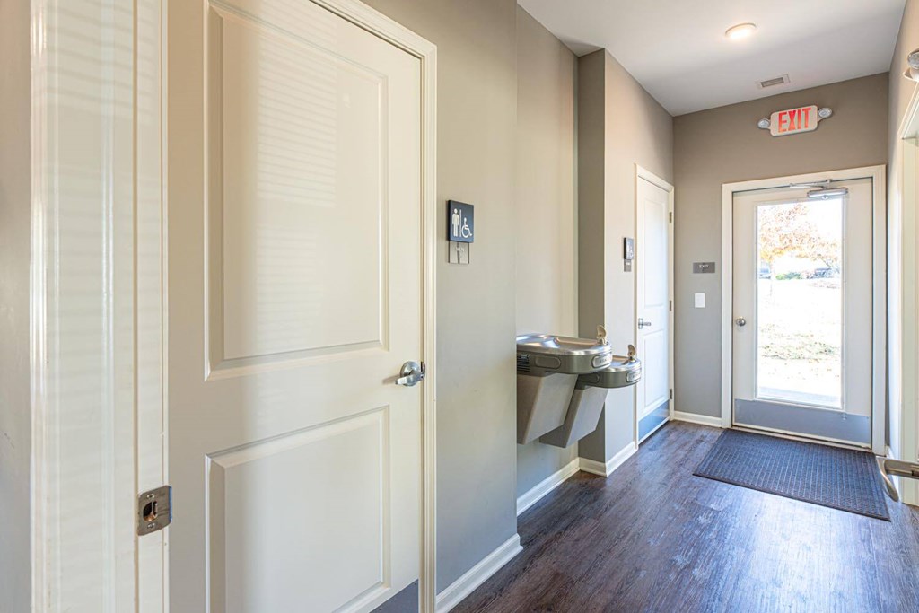 A hallway with a white door and a red exit sign above it.
