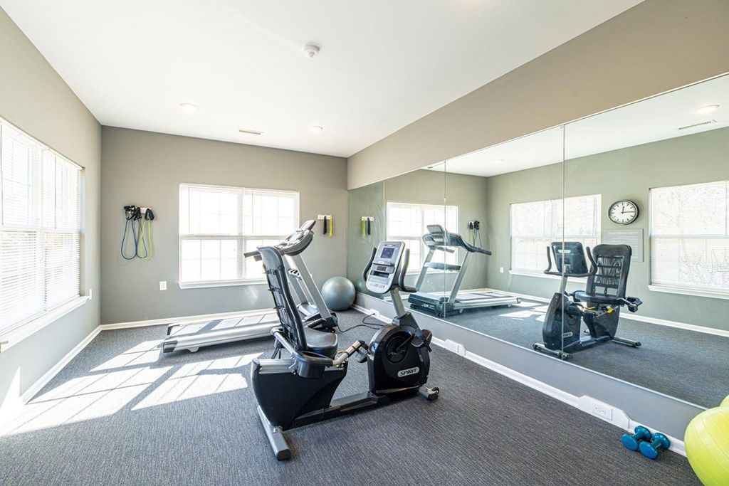 A spacious home gym with a treadmill, elliptical machines, and a weight bench.