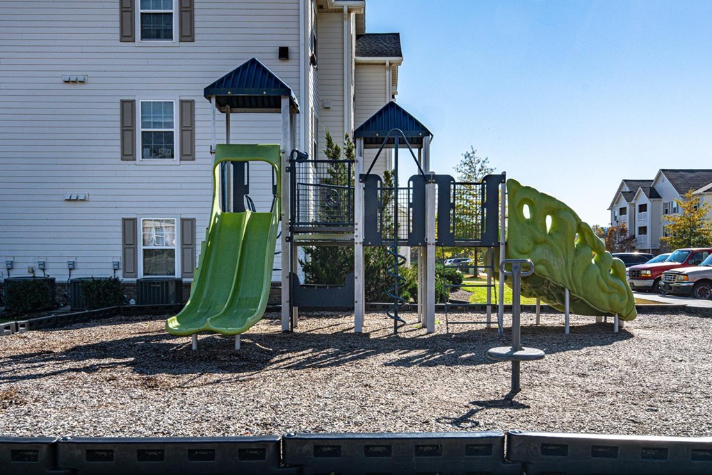 A playground with a green slide and a blue roofed structure.