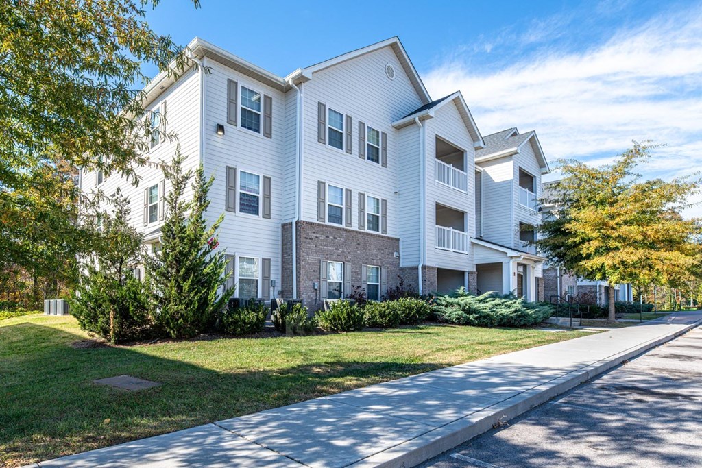 A white apartment building with a green lawn in front.