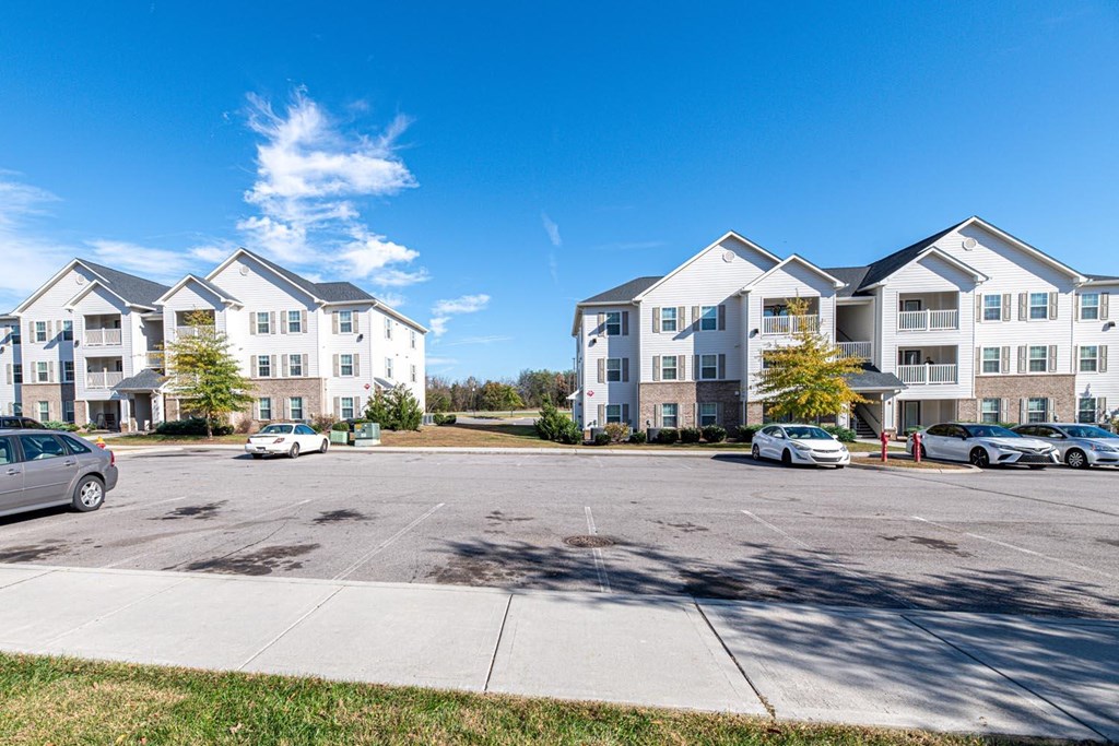 A sunny day at a parking lot in front of apartment buildings.