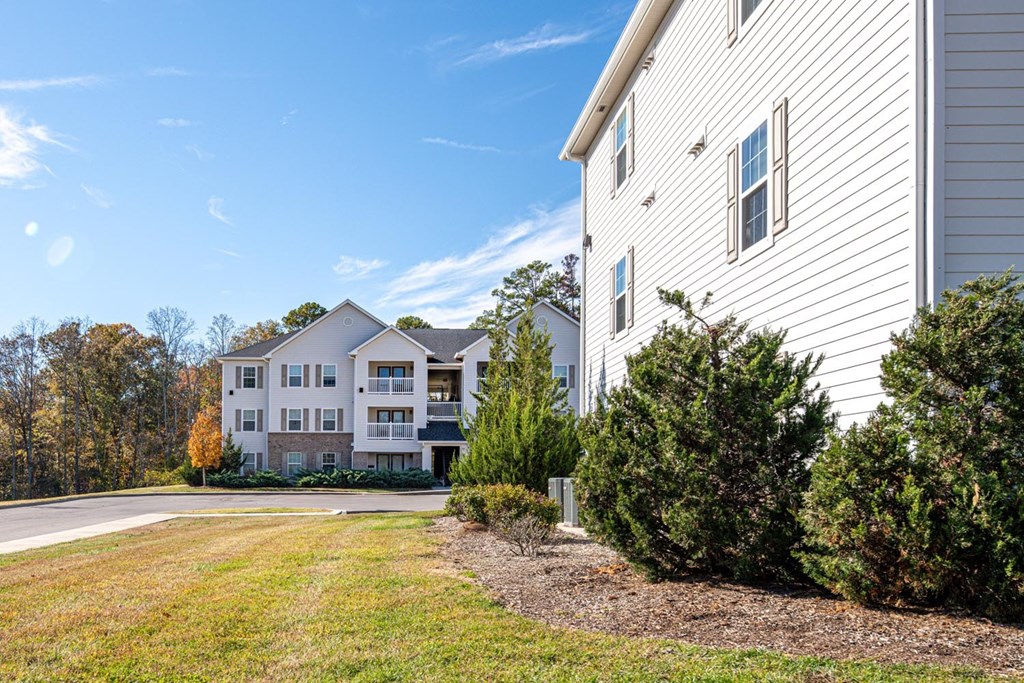 A large white house with a grey roof and a green lawn in front.