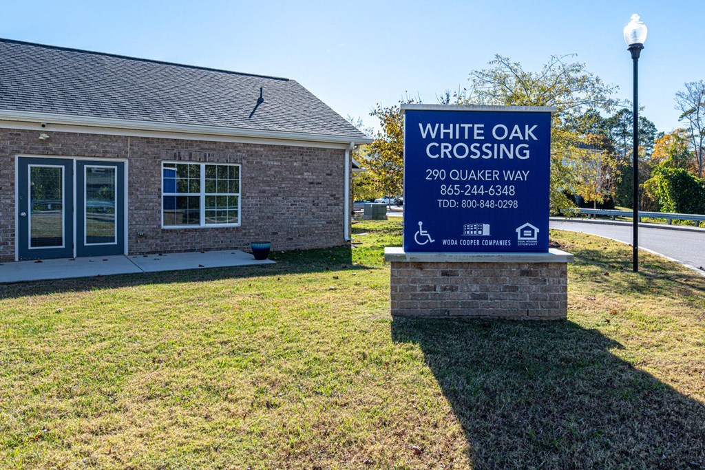 A sign for White Oak Crossing stands in front of a building.