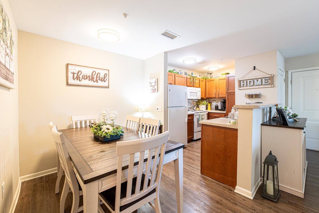 A kitchen with a dining table and chairs in front of a wall with a sign that says Thankful.