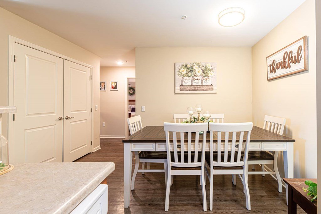 A dining room with a table set for two and a sign on the wall that says "thankful".