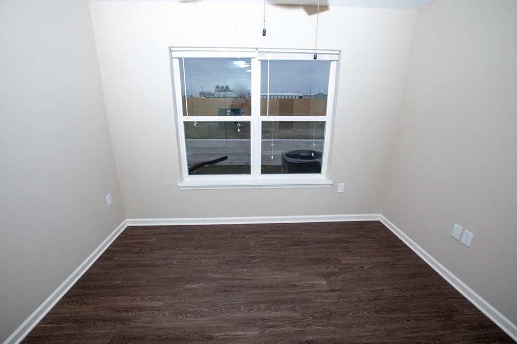 a empty room with a window and wood floors