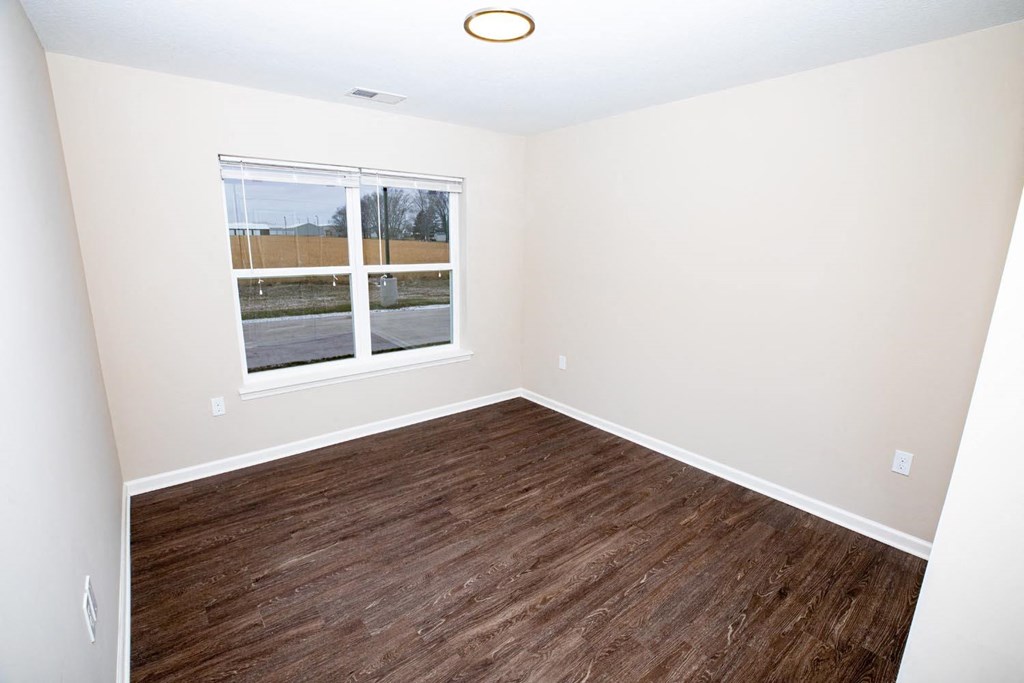 an empty room with a window and wood flooring