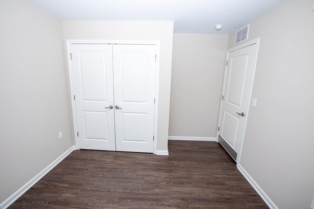 a bedroom with white closets and a wood floor
